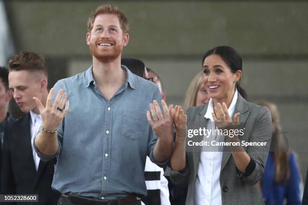 Prince Harry, Duke of Sussex and Meghan, Duchess of Sussex react as they look out towards the heavy rain and storm as they visit the Clontarf...