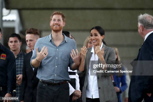 Prince Harry, Duke of Sussex and Meghan, Duchess of Sussex react as they look out towards the heavy rain and storm as they visit the Clontarf...