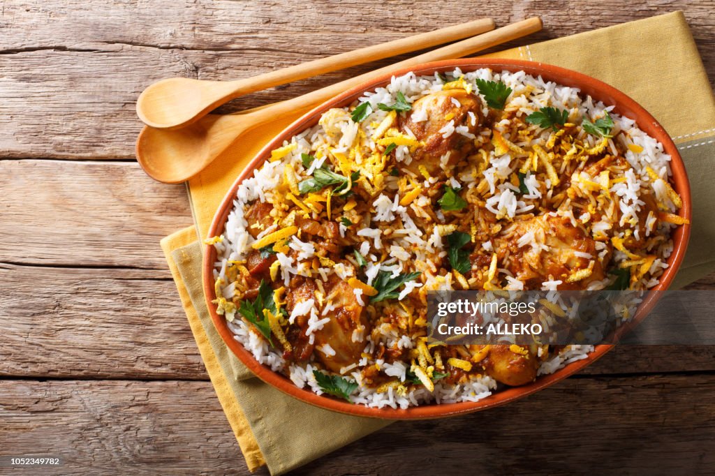 Delicious homemade biryani with chicken, onion, lemon, spices and cilantro close-up. horizontal top view