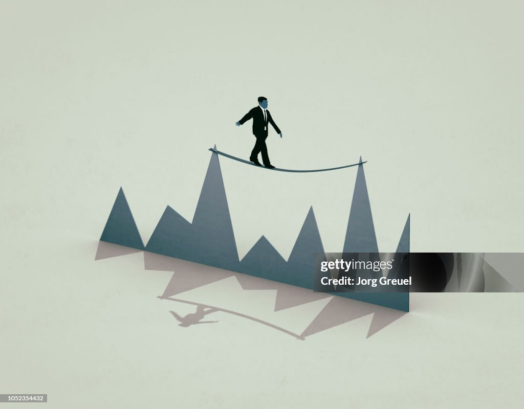 Businessman balancing between two peaks of a graph