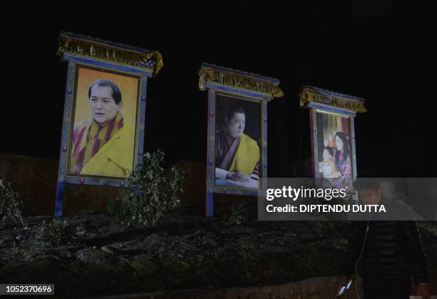 Bhutanese man walks past the pictures of King Jigme Namgyel Wangchuck , his father the former king Jigme Singye Wangchuck, and Queen Jetsun Pema in...