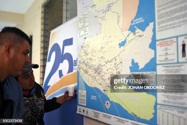 Honduran migrants heading to the United States look at a map of Guatemala at the Casa del Migrante in Guatemala City on October 17, 2018. - A migrant...