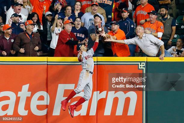 Fan interferes with Mookie Betts of the Boston Red Sox as he attempts to catch a ball hit by Jose Altuve of the Houston Astros in the first inning...
