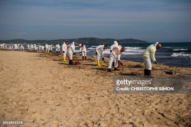 Workers clean hydrocarbon slabs from oil spill from two ships that collided off the waters of Corsica, on Pampelone beach in Ramatuelle, in the Gulf...