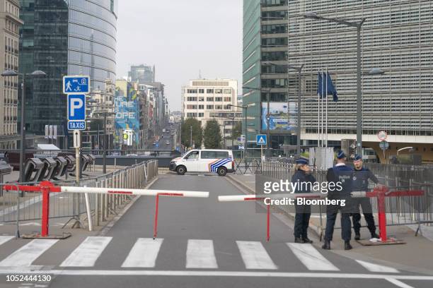 Police officers stand beside a road barrier as the Europa building, which houses the Council of the European Union , left, and the Berlaymont...