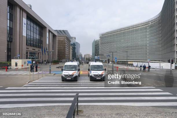 Police vehicles and officers stand beside road barriers as the Europa building, which houses the Council of the European Union , second left, and the...