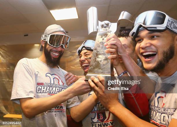 David Price, Mookie Betts, and Eduardo Rodriguez of the Boston Red Sox celebrate with the William Harridge Trophy in the clubhouse after defeating...