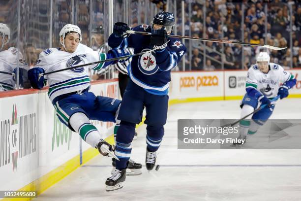 Bo Horvat of the Vancouver Canucks goes flying into the boards after a check by Josh Morrissey of the Winnipeg Jets during third period action at the...
