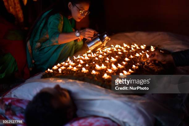 Family member arranging oil lamps on the body of her member during the tenth day of Dashain Durga Puja Festival in Bramayani Temple, Bhaktapur, Nepal...