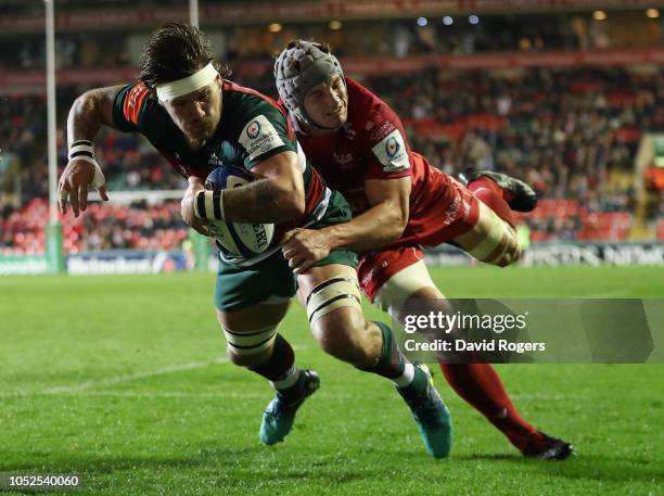 Guy Thompson of Leicester Tigers dives over for a first half try despite being held by Jonathan Davies during the Champions Cup match between...