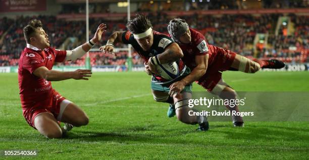 Guy Thompson of Leicester Tigers dives over for a first half try despite being held by Jonathan Davies and Steff Evans during the Champions Cup match...