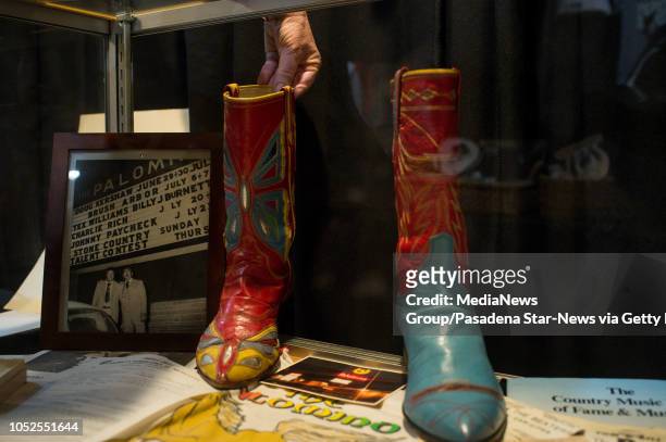 Julie Ann Ream, of Valley Relics Museum, moves a pair of rhinestone-covered suit designer Nudie Cohn's mismatched boots in a display during a one...