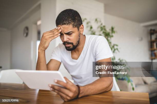 worried mixed race person holding a digital tablet - upset man imagens e fotografias de stock