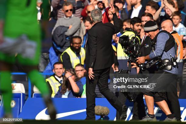 Manchester United's Portuguese manager Jose Mourinho holds up three fingers, indicating the three titles he won with Chelsea, to the crowd after the...