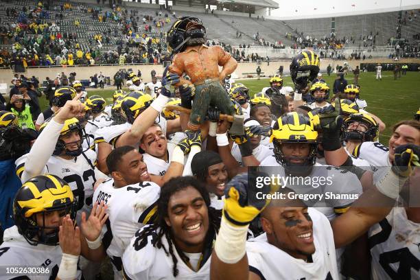 The Michigan Wolverines celebrate winning the Paul Bunyan trophy with a 21-7 win over the Michigan State Spartans at Spartan Stadium on October 20,...