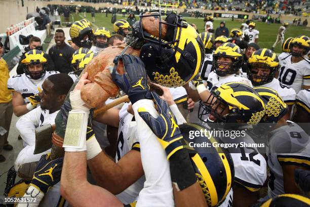 The Michigan Wolverines celebrate winning the Paul Bunyan trophy with a 21-7 win over the Michigan State Spartans at Spartan Stadium on October 20,...