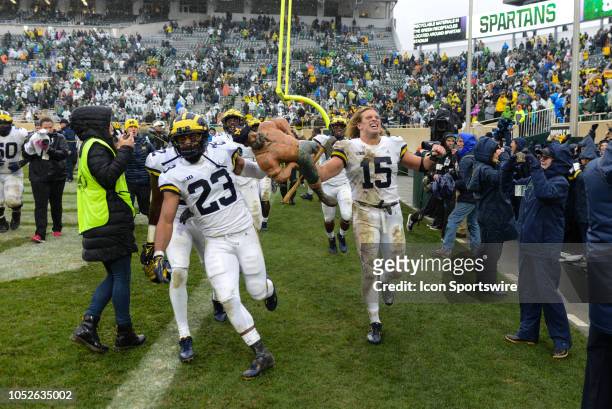 Michigan Wolverines linebacker Chase Winovich and safety Tyree Kinnel race around the field with the Paul Bunyan trophy following a Big Ten...