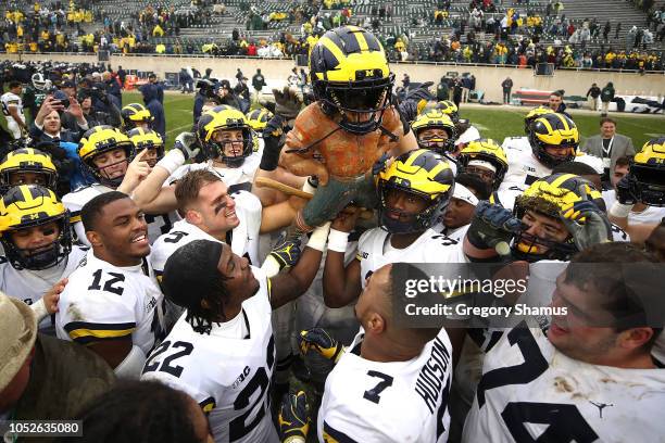 The Michigan Wolverines celebrate winning the Paul Bunyan trophy with a 21-7 win over the Michigan State Spartans at Spartan Stadium on October 20,...