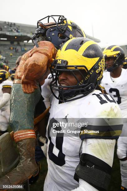 Devin Bush of the Michigan Wolverines carries the Paul Bunyan trophy off the field after beating the Michigan State Spartans 21-7 at Spartan Stadium...