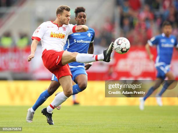 Benedikt Saller of Jahn Regensburg is challenged by Joevin Jones of SV Darmstadt 98 during the Second Bundesliga match between SSV Jahn Regensburg...