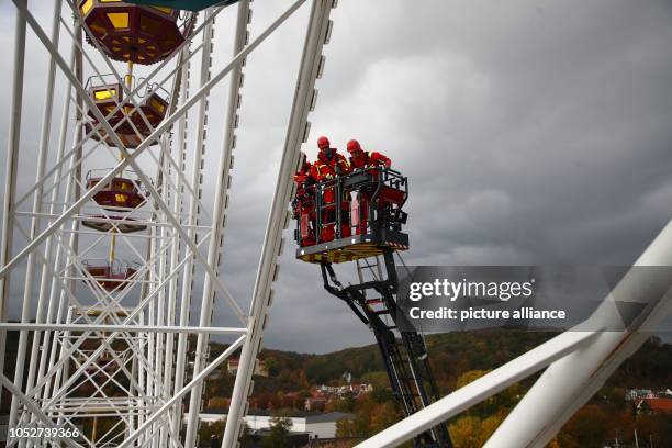 October 2018, Thuringia, Gera: Firefighters practice rescuing people from a gondola on the Ferris wheel at the folk festival. The top gondola of the...