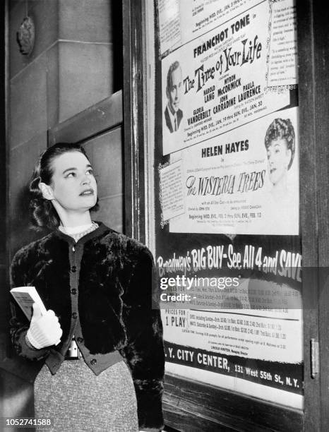 Photo taken in January 1955 shows US actress and fashion designer Gloria Vanderbilt posing next the poster of the play "The time of your life" at the...