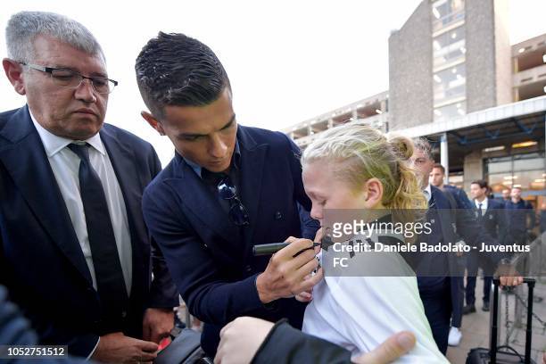 Juventus player Cristiano Ronaldo signs a young girls shirt before traveling to England ahead of the UEFA Champions League match against Manchester...