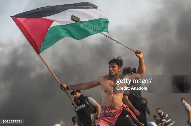 Palestinians throw stones and burn tyres in response to Israeli forces' intervention as they gather to support the maritime demonstration to break...