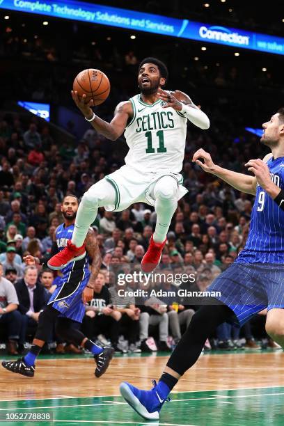 Kyrie Irving of the Boston Celtics goes up for a layup while guarded by Nikola Vucevic of the Orlando Magic during a game at TD Garden on October 22,...