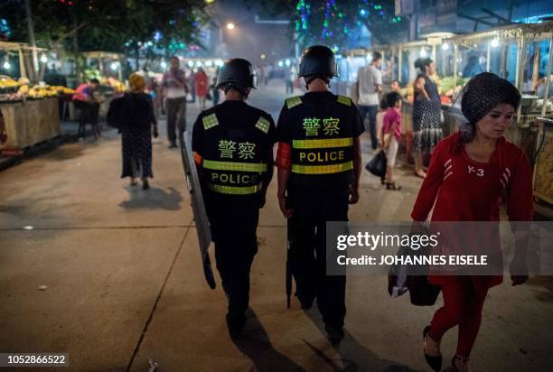 This picture taken on June 25, 2017 shows police patrolling in a night food market near the Id Kah Mosque in Kashgar in China's Xinjiang Uighur...