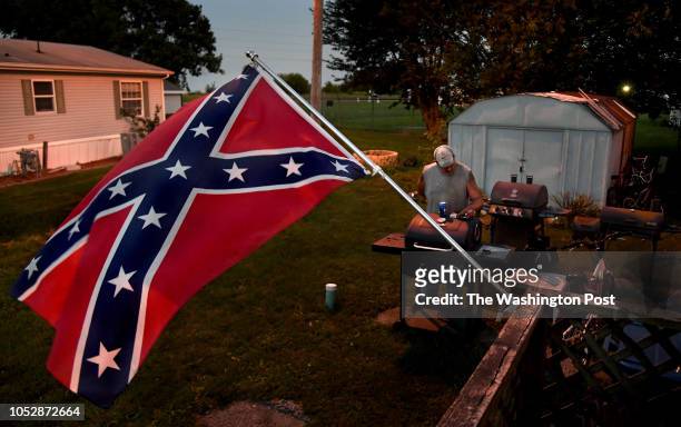 Brent Lowe checks his phone in the yard of his mobile home where a Confederate flag flies daily. Lowe feels that flying the Confederate flag is more...
