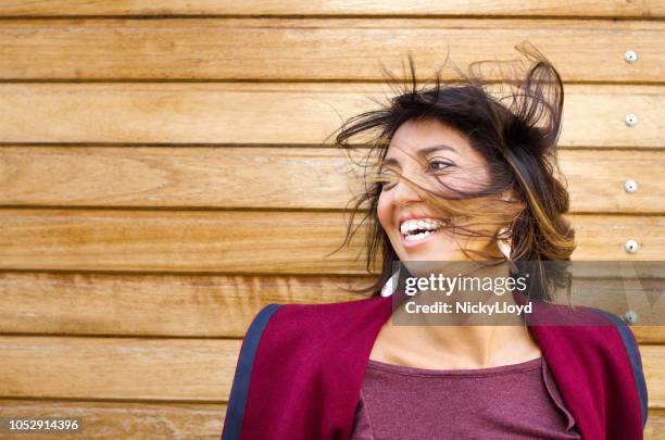 beautiful mixed race woman laughing as the wind blows her hair - maroon hair stock pictures, royalty-free photos & images