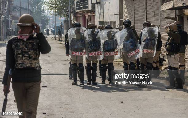 Indian government forces hold shield to save themselves from the stones of Kashmiri Muslin protesters during a protest near a gun battle site, after...