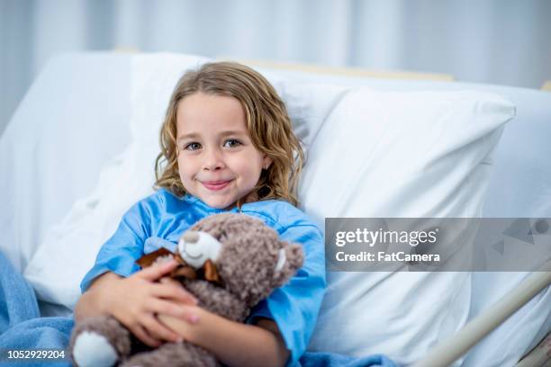 laying with teddy bear - child in hospital bed stock pictures, royalty-free photos & images