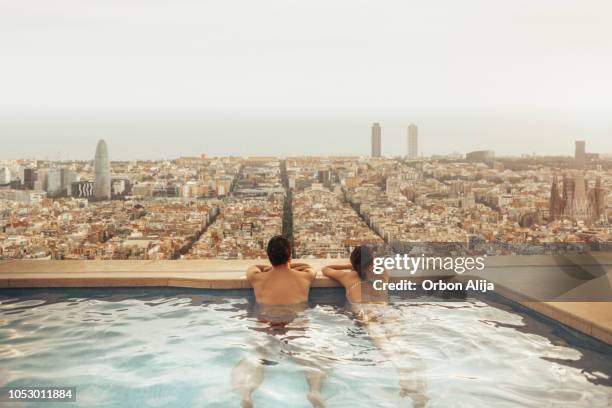 pareja relajante en la azotea del hotel mirando el horizonte de la ciudad de barcelona. composición de la foto. - luxury fotografías e imágenes de stock