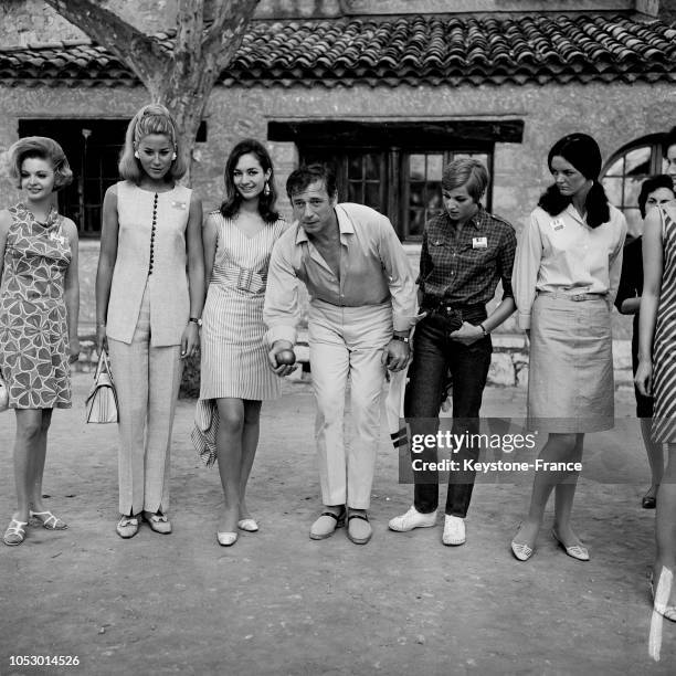 Yves Montand jouant aux boules, entouré de Miss Irlande, Miss Angleterre, Miss Espagne et Miss Europe, à Saint-Paul-de-Vence, France, en juin 1967.