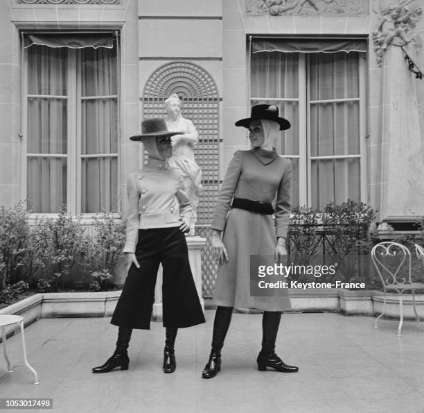 Deux modèles de la collection hiver de Jacques Esterel, cape courte sur jupe-culotte et blouson et robe limousine en crèpe jaune, à Paris, France, le...
