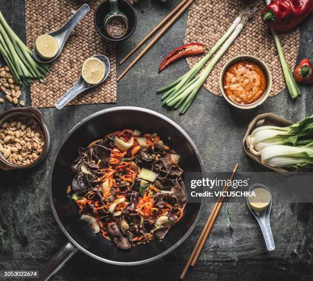 wok with cut vegetables and chinese mu err mushrooms on kitchen table with asian cuisine ingredients - wok stockfoto's en -beelden