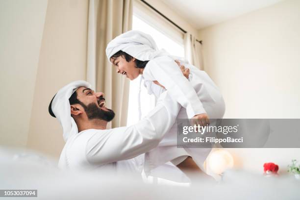 arab man playing with his son at home - dubai family stock pictures, royalty-free photos & images