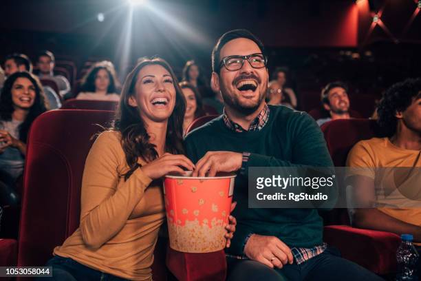 happy couple eating popcorn - film industry stock pictures, royalty-free photos & images