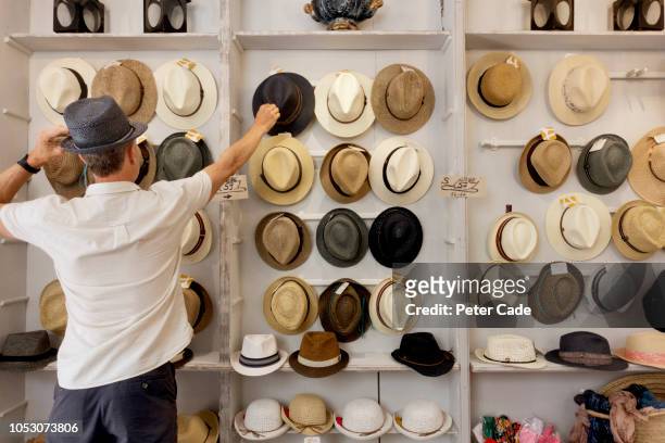 man choosing a hat in shop - hat stock pictures, royalty-free photos & images