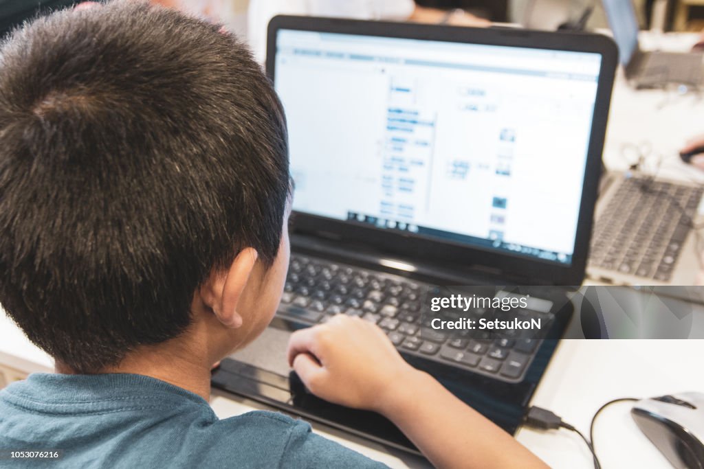 Asian boy learning programming with laptop, close up