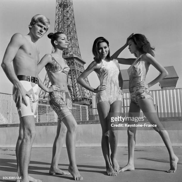 Devant la Tour Eiffel, quatre mannequins homme et femmes portant des costumes de bain pour l'été 1968, à Paris, France, le 6 novembre 1967.