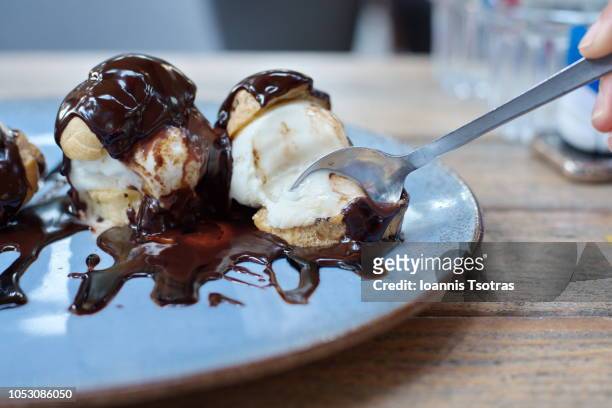 eating profiterole dessert with spoon - profiterole stock-fotos und bilder
