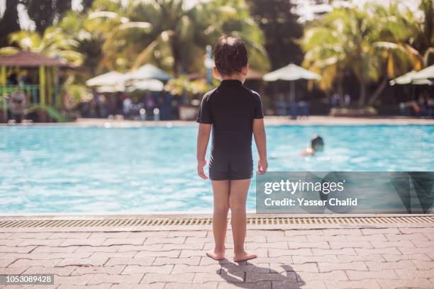 boy standing by swimming pool - boy swimming pool stock pictures, royalty-free photos & images