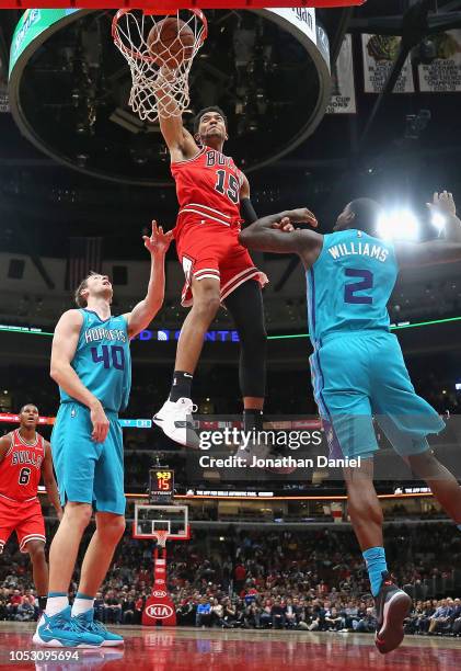 Chandler Hutchison of the Chicago Bulls dunks over Cody Zeller and Marvin Williams of the Charlotte Hornets at the United Center on October 24, 2018...