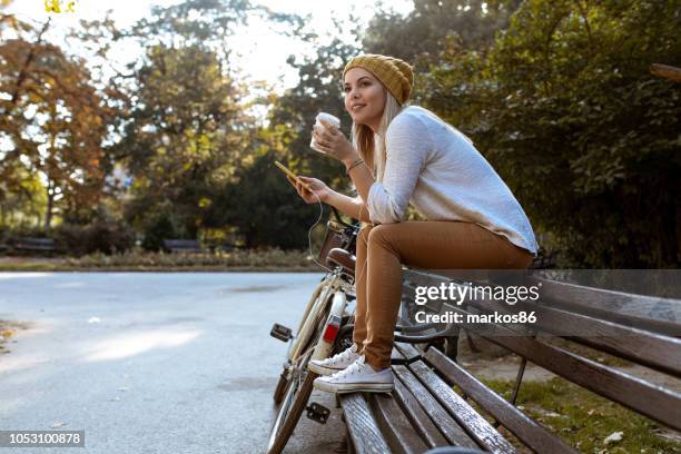 aantrekkelijke vrouw nemen van een koffie pauze - park bench stockfoto's en -beelden