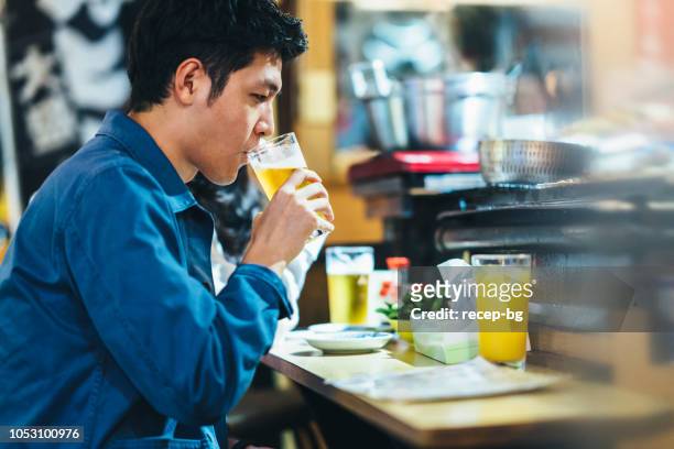 asian man tourist drinking beer in street food counter at night - izakaya stock pictures, royalty-free photos & images