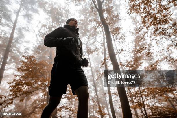 young man running in a forest - young men running stock pictures, royalty-free photos & images