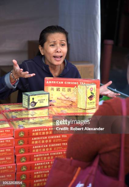 Chinese woman selling American ginseng tea at a street festival makes a sales pitch to a potential customer in Chinatown, San Francisco, California.